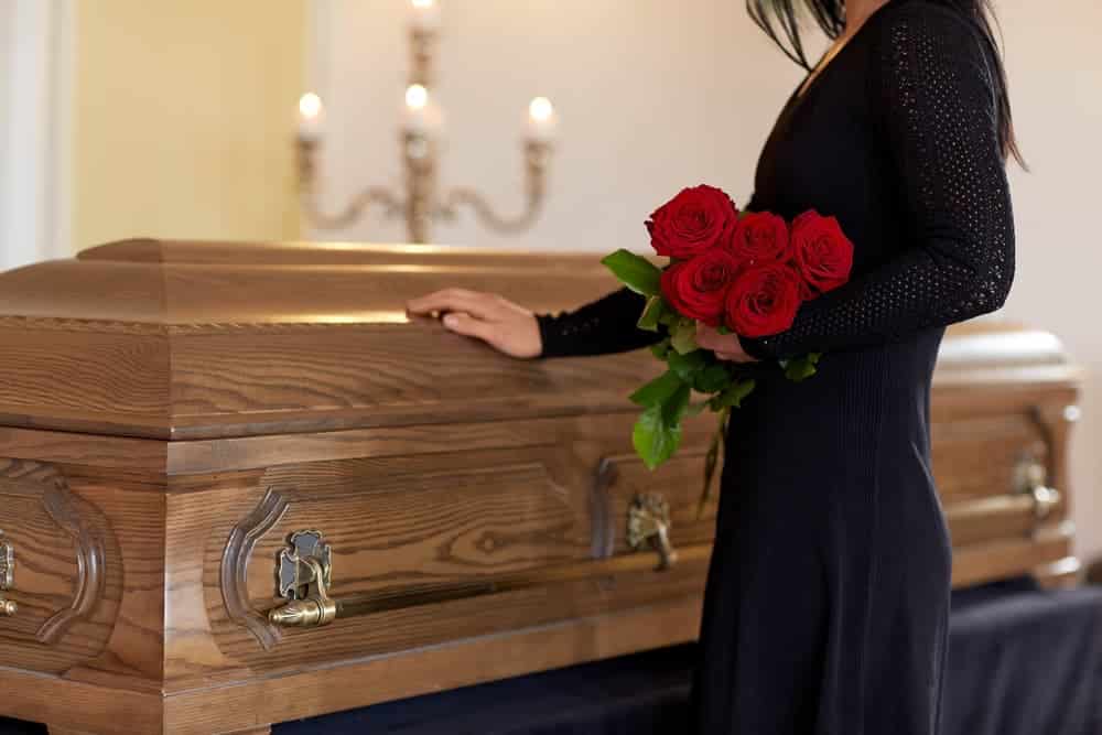 woman with hand on casket mourning