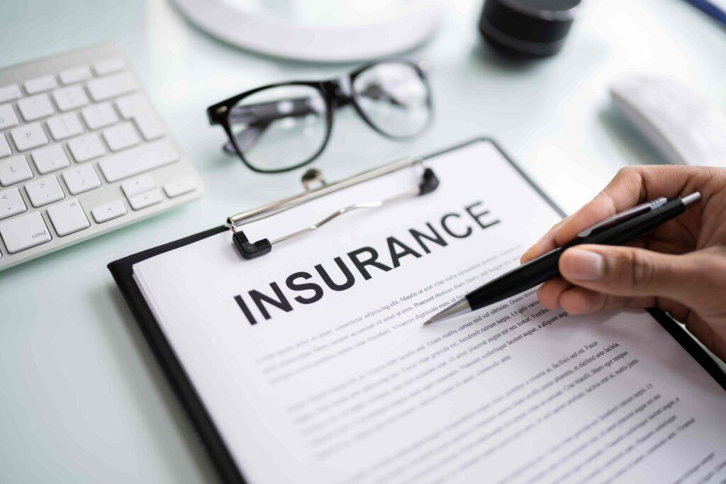 Insurance document on clipboard with pen and glasses on desk. Insurance document on clipboard with pen and glasses on desk.